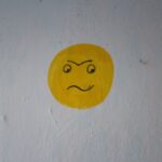 a yellow smiley face painted on a white wall