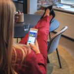 woman in red jacket holding white smartphone